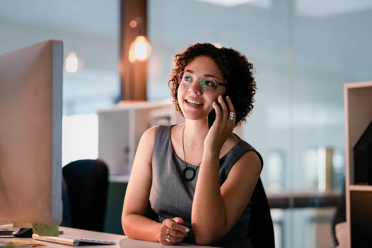 Woman smiling on a phone call at her desk.