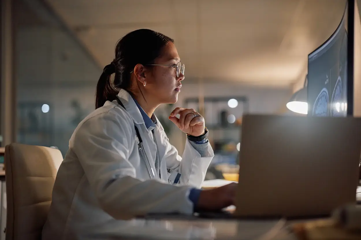 Medical professional analyzing patient data on a computer, focused and engaged in research or diagnostics.