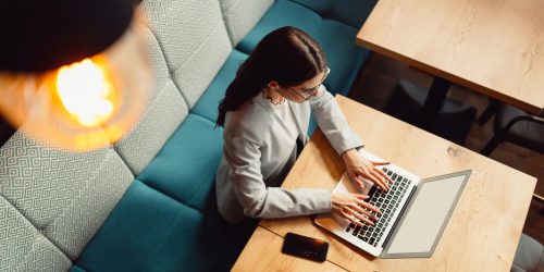 Top angle view of woman while using laptop at cafe.
